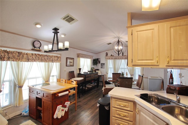 kitchen with a notable chandelier, lofted ceiling, light countertops, hanging light fixtures, and a sink