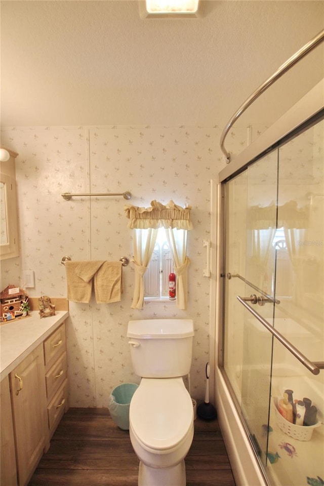 full bathroom featuring toilet, wallpapered walls, enclosed tub / shower combo, and wood finished floors