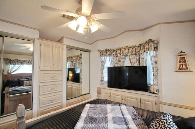 bedroom with multiple closets, ceiling fan, visible vents, and crown molding