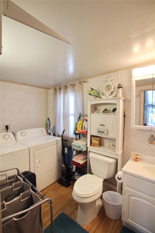 bathroom with vanity, separate washer and dryer, wood finished floors, and toilet