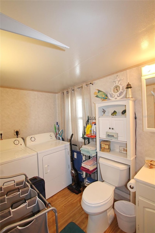 bathroom featuring toilet, separate washer and dryer, wood finished floors, and vanity