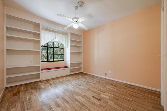 spare room with built in features, ceiling fan, and light wood-type flooring