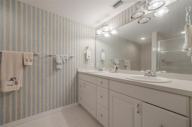 bathroom with wallpapered walls, a stall shower, visible vents, and a sink