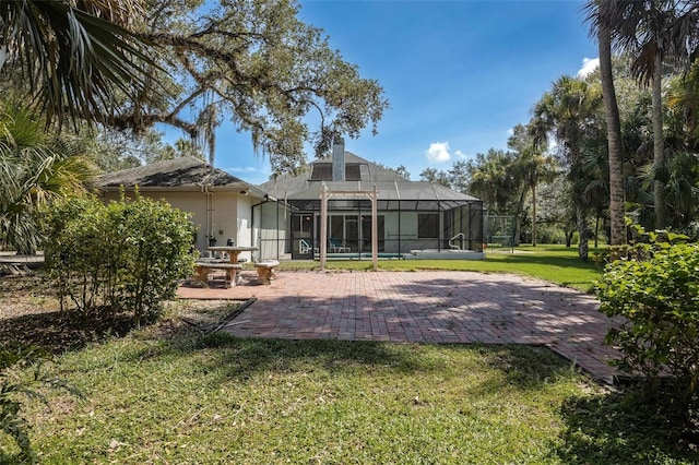 rear view of house featuring a yard, a chimney, stucco siding, a lanai, and a patio area