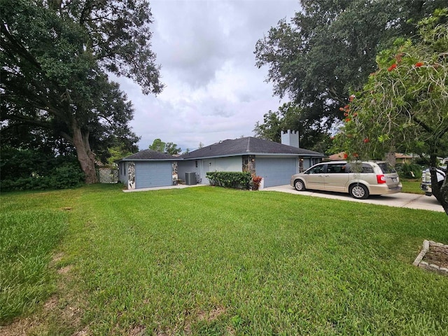 view of yard with a garage and central AC