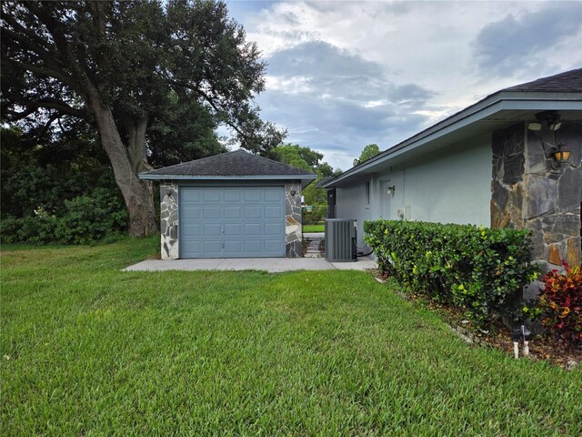 view of yard featuring an outbuilding, a garage, and central air condition unit