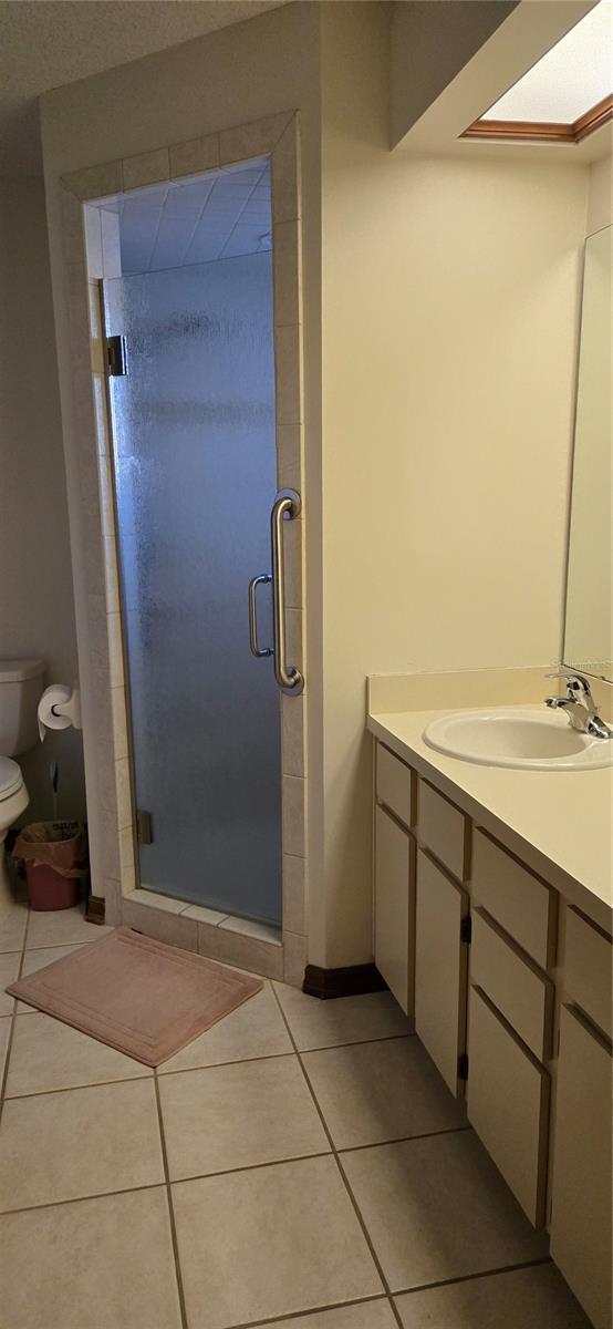 bathroom with vanity, tile patterned floors, a shower with door, and toilet