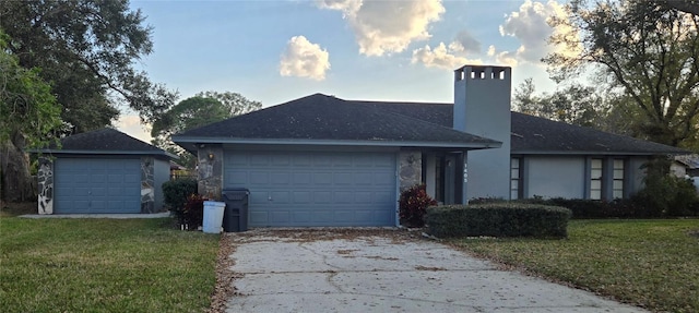 ranch-style home featuring a garage and a lawn