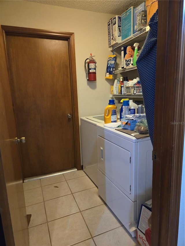 washroom featuring separate washer and dryer, a textured ceiling, and light tile patterned floors