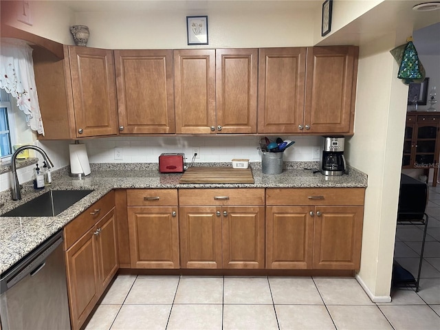 kitchen with tasteful backsplash, dishwasher, light tile patterned floors, light stone countertops, and sink