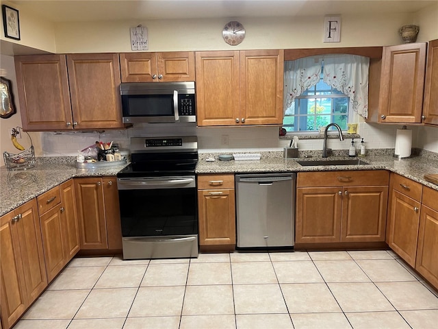 kitchen featuring light tile patterned floors, stainless steel appliances, sink, and dark stone counters