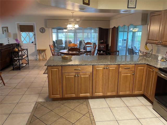 kitchen with a notable chandelier, plenty of natural light, kitchen peninsula, and light tile patterned flooring