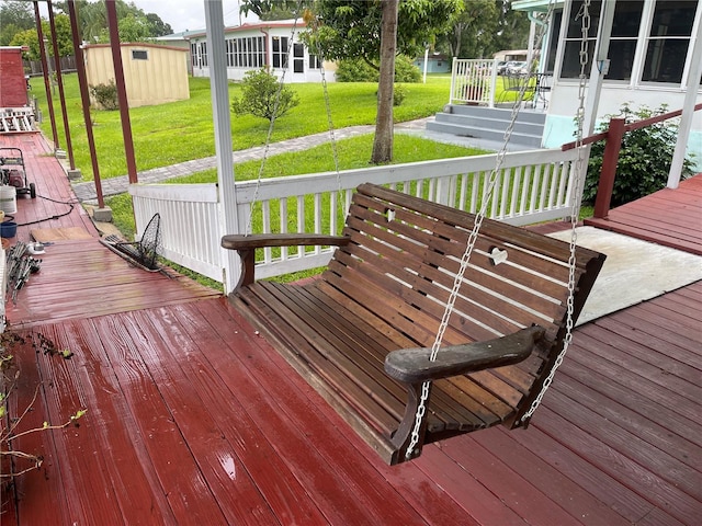 wooden deck with a lawn and a storage unit