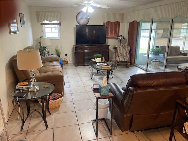 living room with a textured ceiling, light tile patterned floors, and ceiling fan