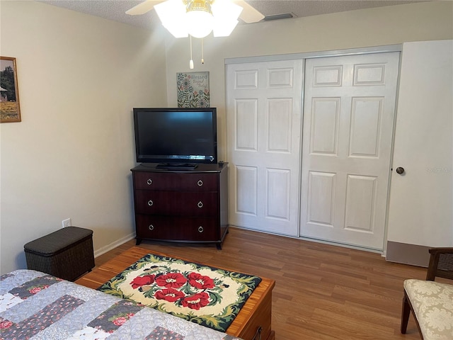 bedroom with a closet, wood-type flooring, ceiling fan, and a textured ceiling