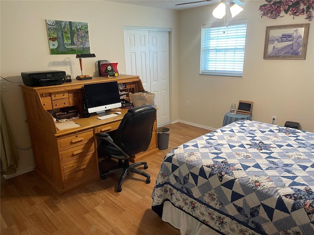 bedroom with light wood-type flooring, ceiling fan, and a closet