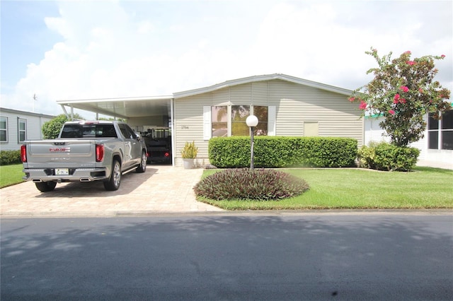 manufactured / mobile home featuring a carport and a front lawn