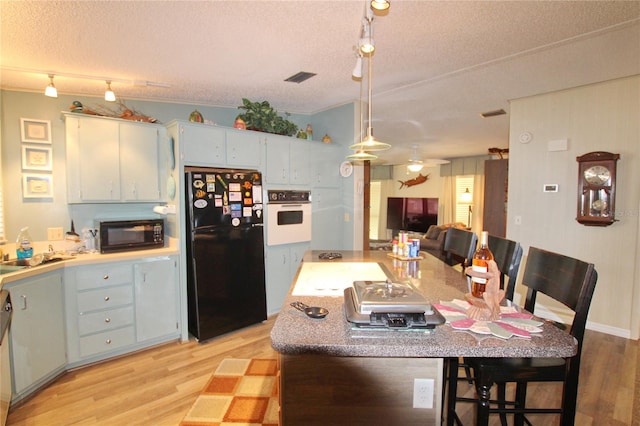 kitchen featuring light hardwood / wood-style flooring, black appliances, and a textured ceiling