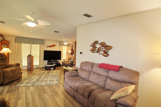 living room featuring a textured ceiling, light hardwood / wood-style flooring, and ceiling fan