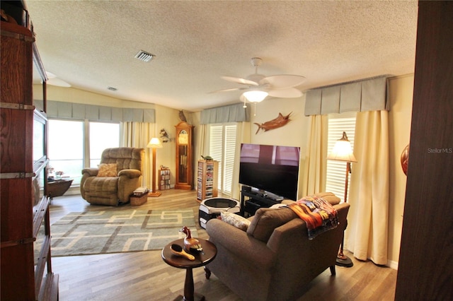 living room featuring a textured ceiling, lofted ceiling, ceiling fan, and light hardwood / wood-style floors