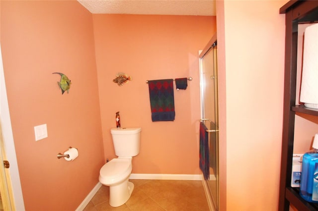 bathroom with tile patterned floors, toilet, a textured ceiling, and a shower with shower door