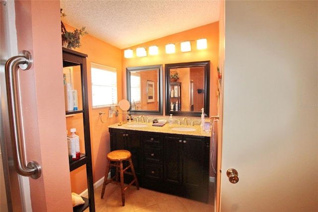 bathroom featuring a textured ceiling, vanity, vaulted ceiling, and tile patterned floors