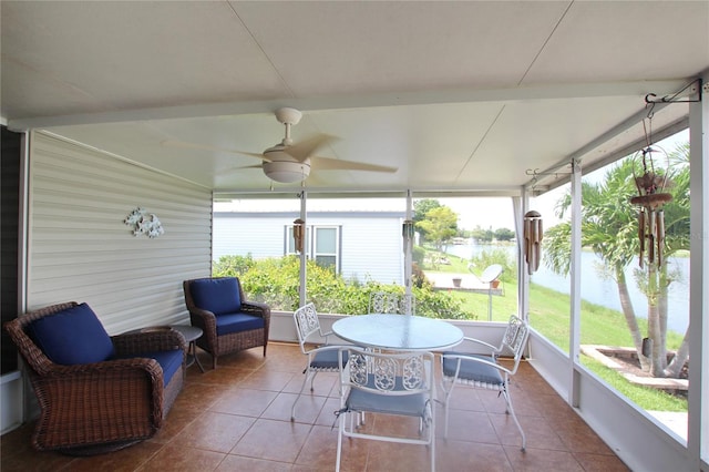 sunroom / solarium with ceiling fan and a water view