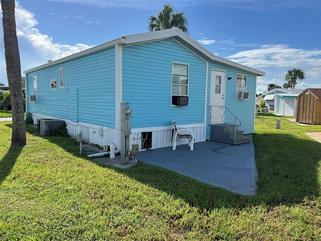 back of property with cooling unit, a lawn, a shed, and a patio