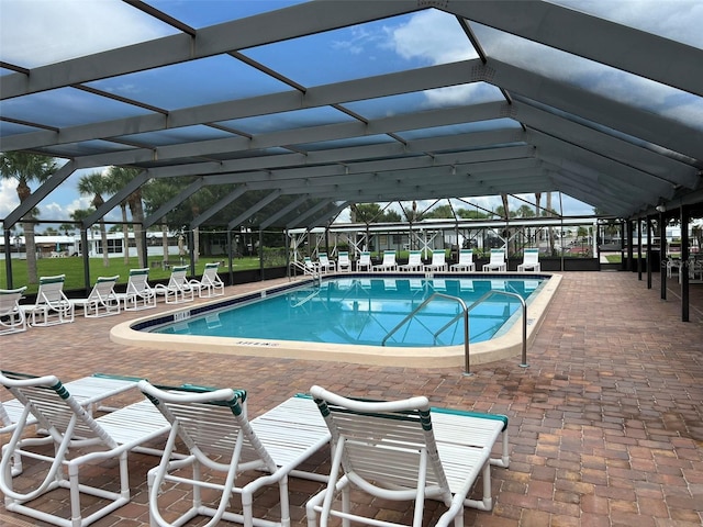 view of pool with glass enclosure and a patio