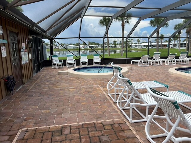 view of pool featuring a lanai, a jacuzzi, a patio, and a water view