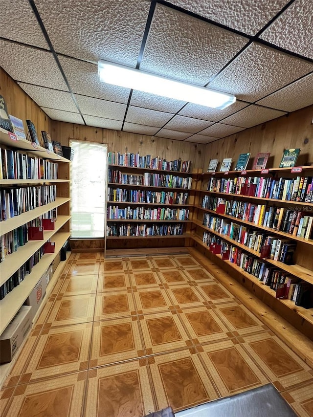 6697 SE 51st Ln Iii, Unit Iii, Okeechobee, FL 34974 - unfurnished room featuring a drop ceiling, wooden walls, and wall of books
