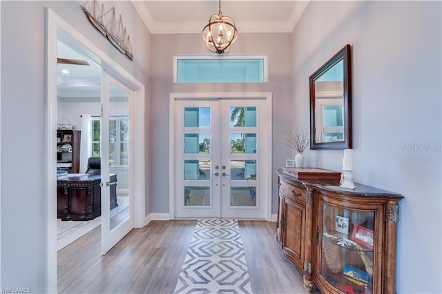 entrance foyer featuring crown molding, french doors, wood-type flooring, and a chandelier