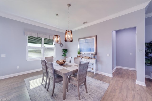 dining area with ornamental molding and light hardwood / wood-style floors