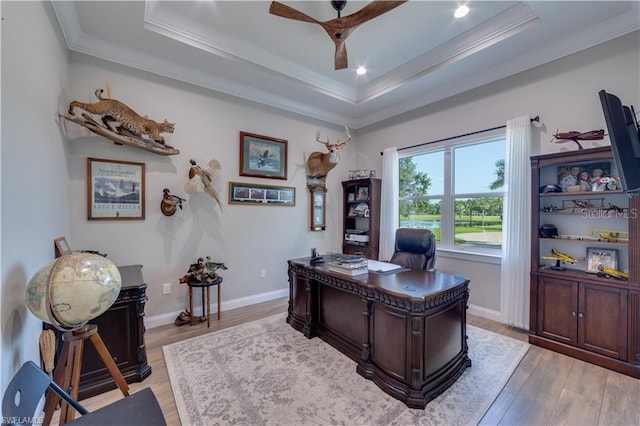 office area featuring light wood-type flooring, crown molding, a tray ceiling, and ceiling fan