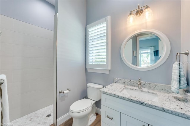 bathroom featuring vanity, toilet, plenty of natural light, and a tile shower