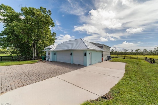 garage featuring a lawn and a rural view