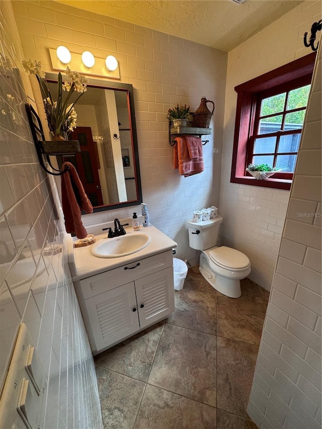 bathroom featuring tile walls, a textured ceiling, vanity, and toilet