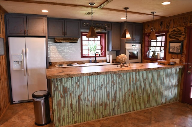 kitchen featuring hanging light fixtures, white appliances, sink, and kitchen peninsula