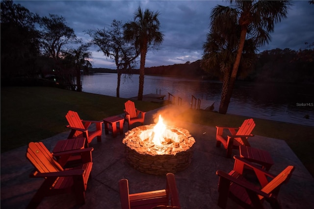 patio terrace at dusk featuring a water view and an outdoor fire pit