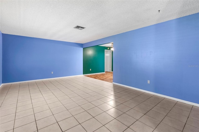 spare room featuring light tile patterned floors and a textured ceiling