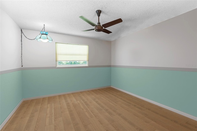 unfurnished room with ceiling fan, a textured ceiling, and light wood-type flooring