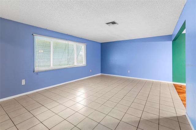 tiled empty room featuring a textured ceiling