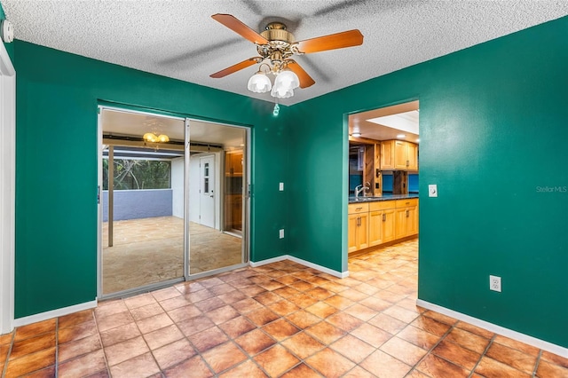 unfurnished bedroom with ceiling fan, sink, a textured ceiling, and a closet