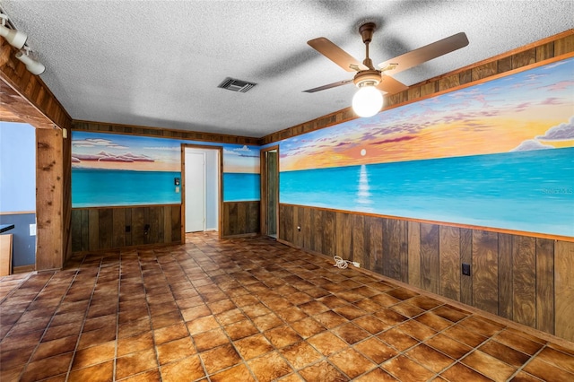 unfurnished living room with wooden walls, ceiling fan, and a textured ceiling