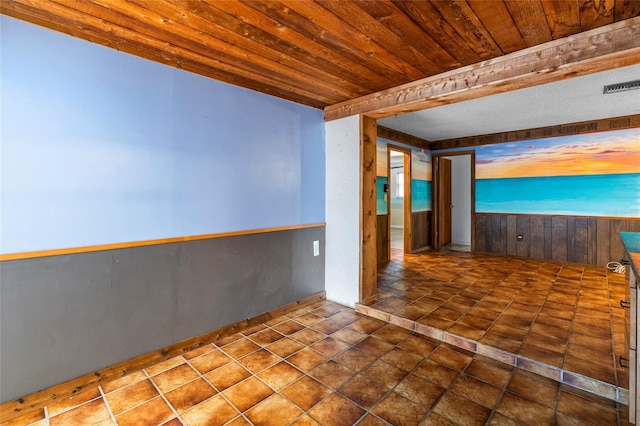 empty room with dark tile patterned flooring, wood walls, and wood ceiling