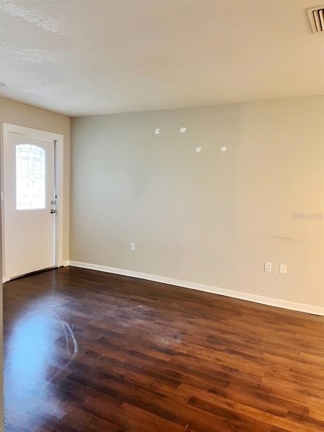 empty room featuring a textured ceiling and dark wood-type flooring