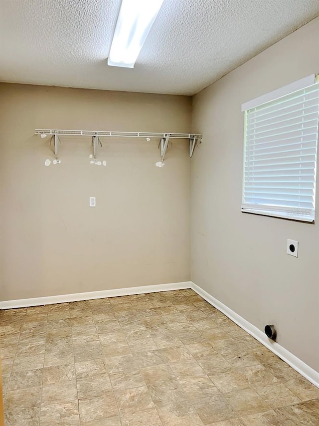 washroom with electric dryer hookup and a textured ceiling