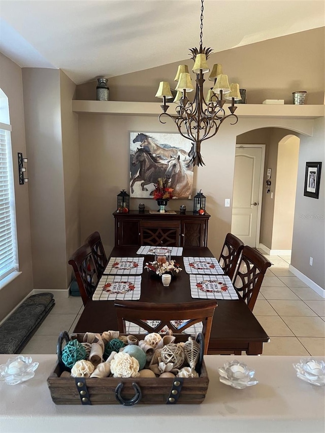 tiled dining room featuring a notable chandelier, vaulted ceiling, and plenty of natural light