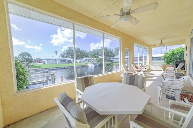 sunroom / solarium featuring a water view and ceiling fan