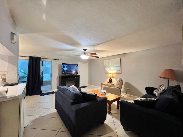 living room featuring a textured ceiling, light tile patterned floors, and ceiling fan